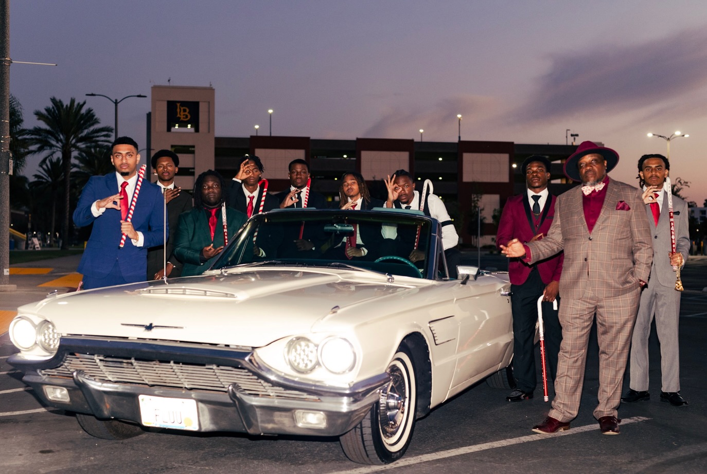 Chapter brothers posing beside a white classic convertible at dusk